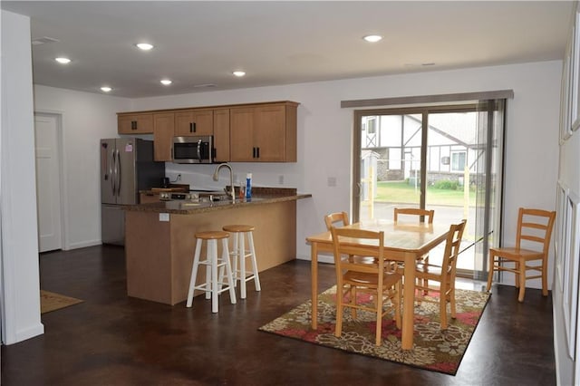 kitchen with kitchen peninsula, a breakfast bar, dark stone counters, and appliances with stainless steel finishes