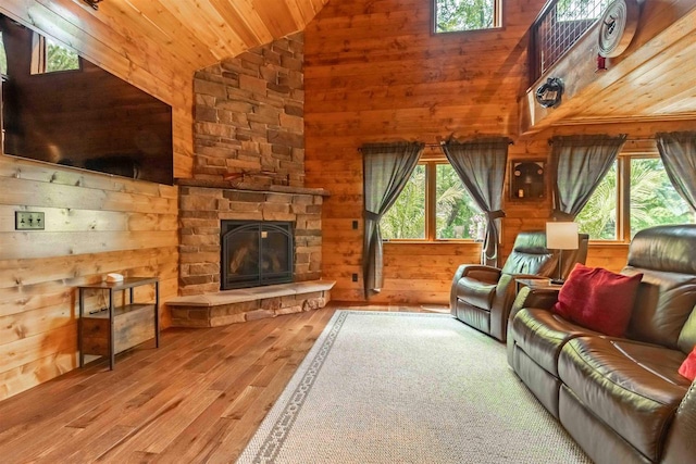 living room featuring high vaulted ceiling, wooden walls, a fireplace, plenty of natural light, and wooden ceiling