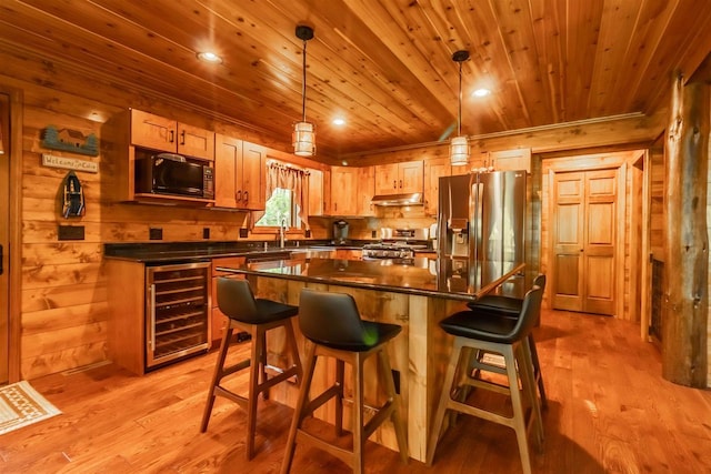 kitchen featuring wine cooler, pendant lighting, a kitchen island, and appliances with stainless steel finishes