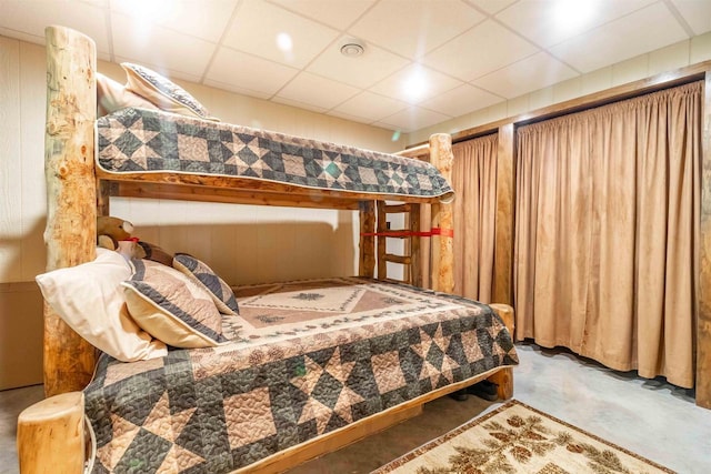 bedroom featuring a drop ceiling and concrete floors