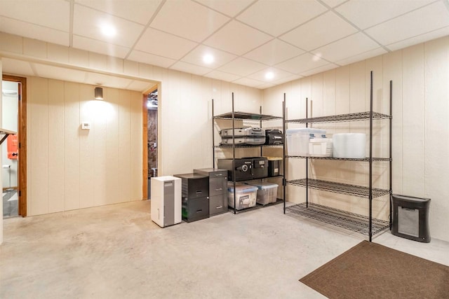 basement with a paneled ceiling and wood walls