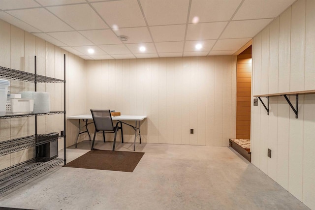 office featuring a paneled ceiling and wood walls