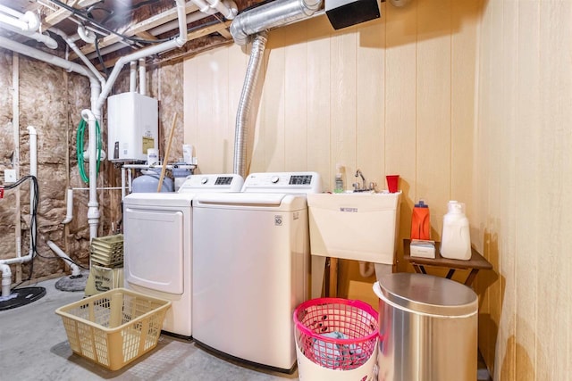 washroom featuring water heater, sink, washing machine and clothes dryer, and wooden walls