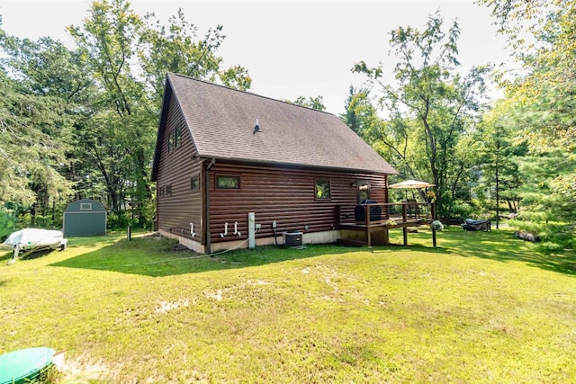 back of house with a yard, central AC unit, and a storage shed