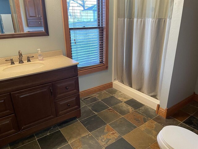 bathroom with tile patterned flooring, plenty of natural light, toilet, and vanity