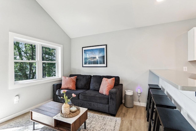 living room featuring light wood-style flooring, baseboards, and vaulted ceiling