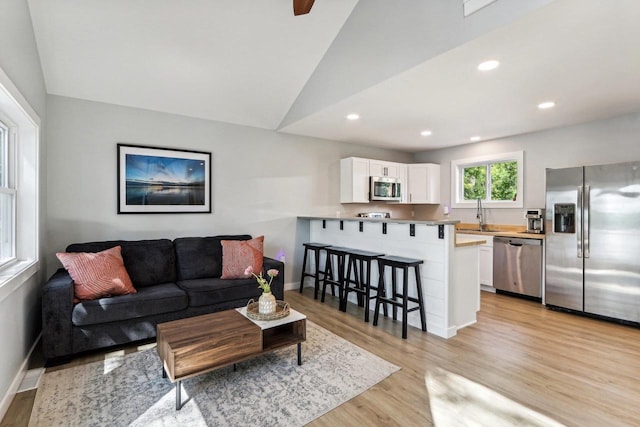 living room with baseboards, light wood-type flooring, recessed lighting, and lofted ceiling