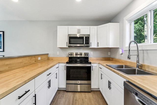 kitchen featuring light wood-type flooring, white cabinetry, a sink, and appliances with stainless steel finishes