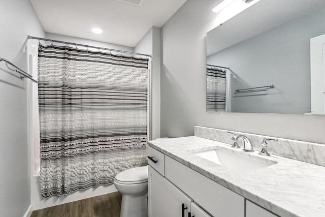 bathroom with shower / bathtub combination with curtain, vanity, toilet, and wood finished floors