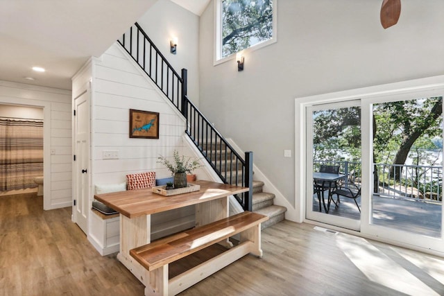 staircase with baseboards, recessed lighting, a towering ceiling, and wood finished floors
