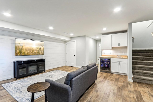 living room with indoor wet bar, wine cooler, recessed lighting, wood finished floors, and stairs
