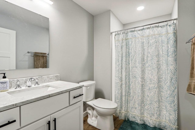 bathroom with curtained shower, vanity, toilet, and wood finished floors