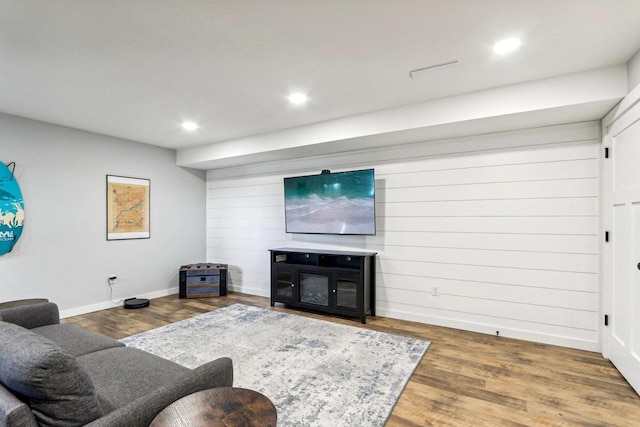 living area featuring wooden walls, baseboards, recessed lighting, and wood finished floors