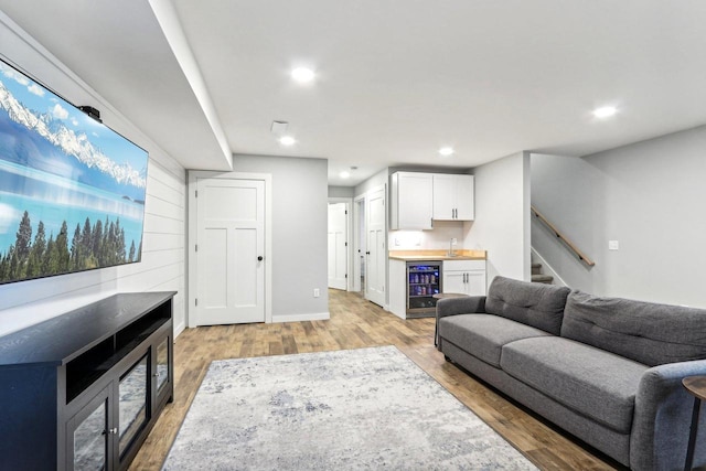 living room with recessed lighting, stairs, bar, light wood-style flooring, and beverage cooler