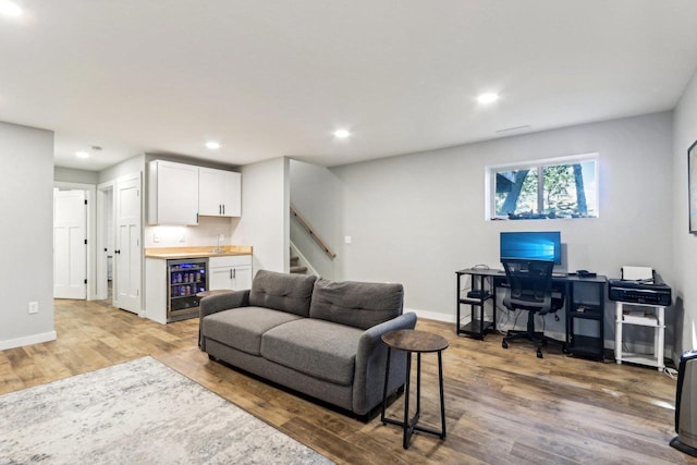 living room featuring bar area, light wood-style floors, recessed lighting, stairway, and beverage cooler