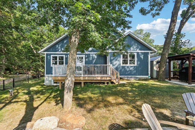 rear view of property with a wooden deck, fence, and a lawn