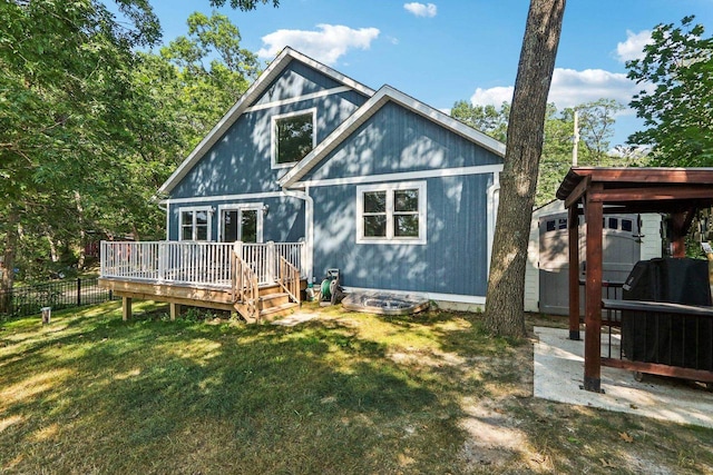 back of house with fence, a deck, and a lawn