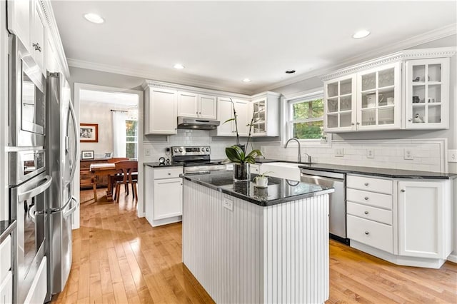 kitchen with white cabinets, ornamental molding, stainless steel appliances, and a kitchen island