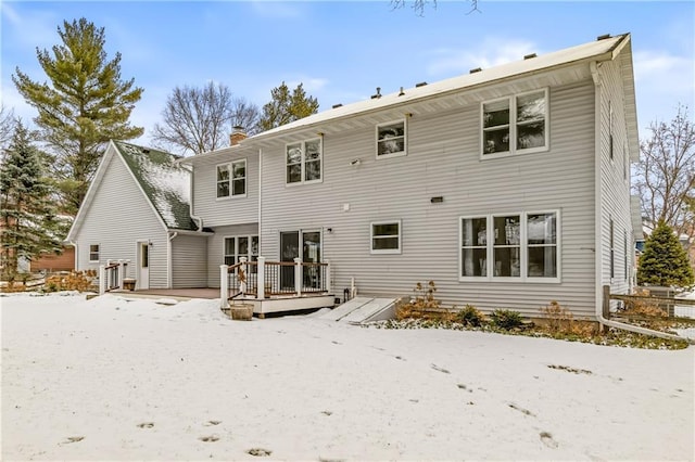 snow covered rear of property with a wooden deck