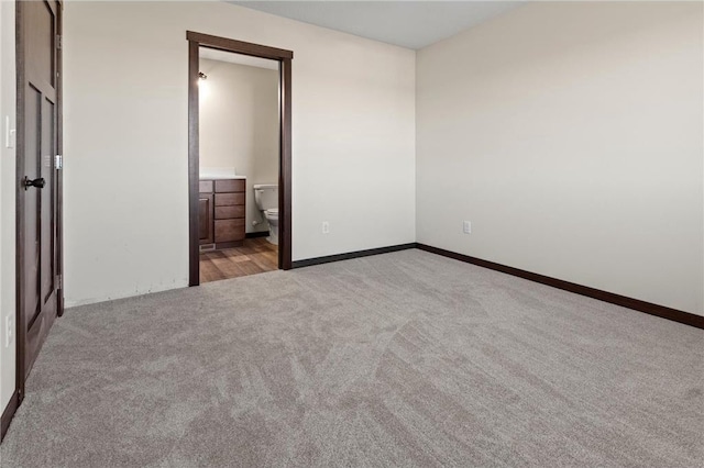 unfurnished bedroom with light carpet and connected bathroom