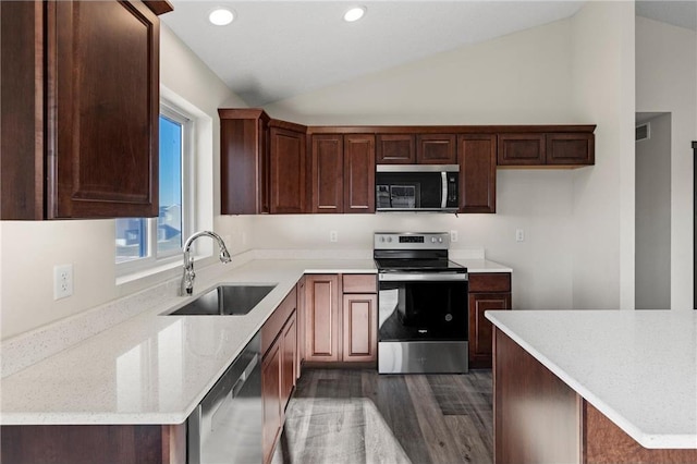 kitchen featuring sink, vaulted ceiling, light stone countertops, appliances with stainless steel finishes, and dark hardwood / wood-style flooring