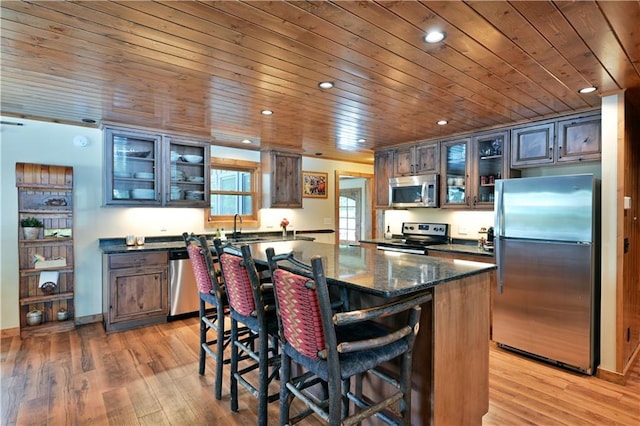 kitchen with a kitchen island, appliances with stainless steel finishes, a breakfast bar, and light hardwood / wood-style flooring