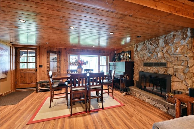 dining room featuring hardwood / wood-style flooring, wooden ceiling, and a fireplace