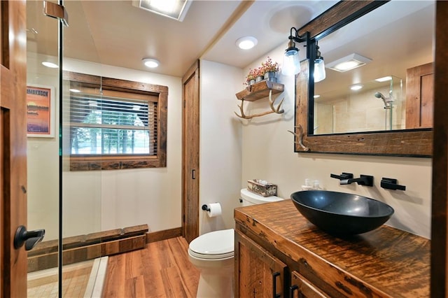 bathroom featuring vanity, toilet, hardwood / wood-style floors, and walk in shower