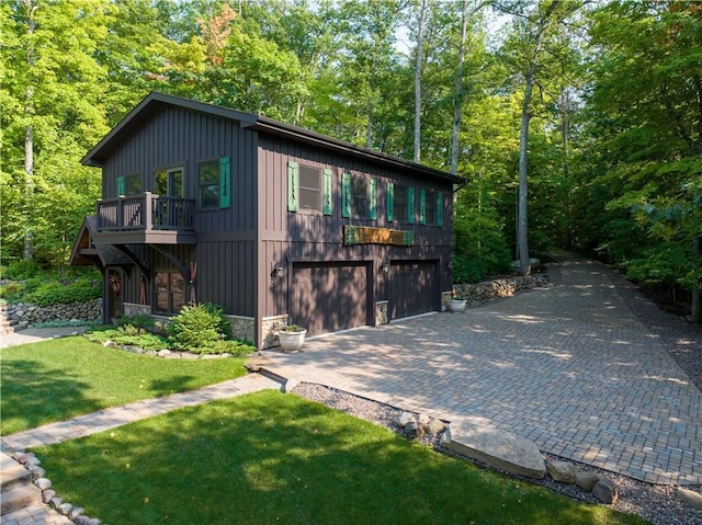 exterior space with a garage, a balcony, and a lawn