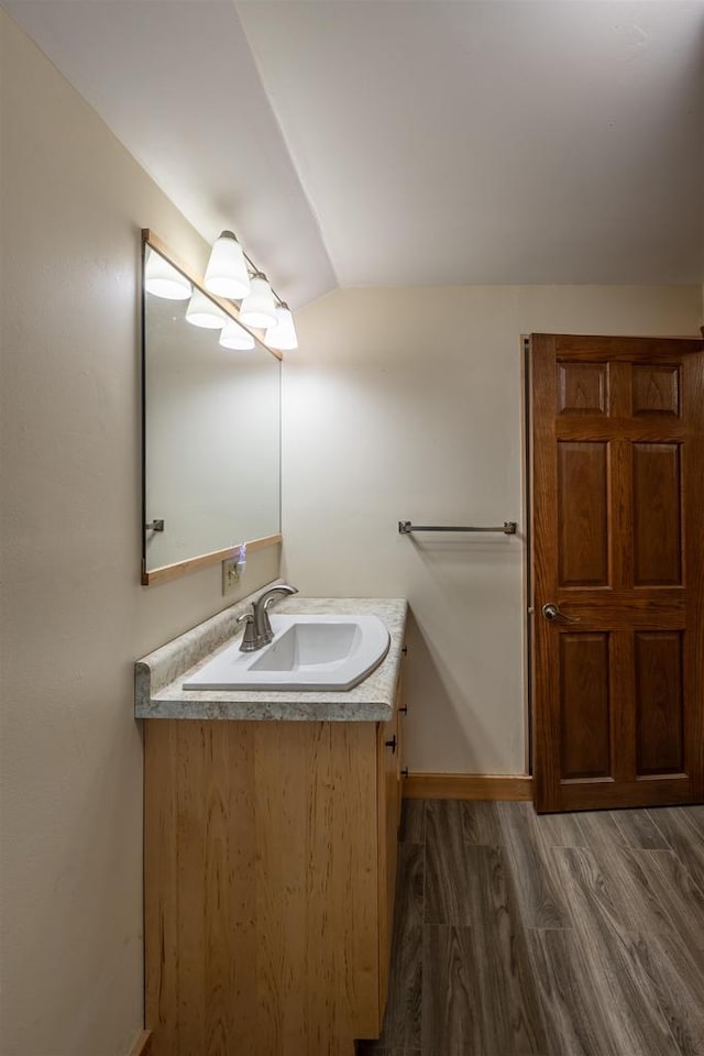 bathroom with vanity, wood-type flooring, and vaulted ceiling