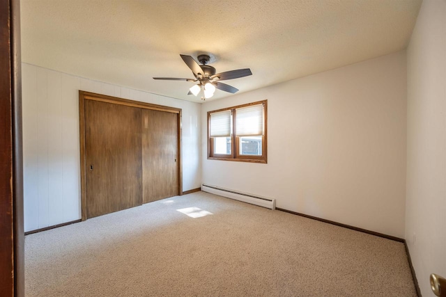 unfurnished bedroom featuring a baseboard radiator, a closet, light colored carpet, and ceiling fan