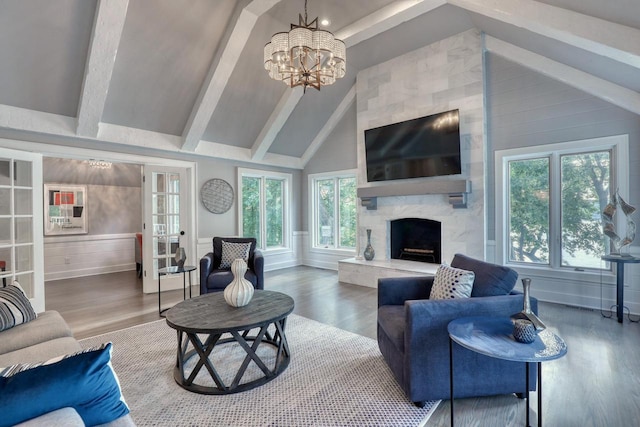 living room featuring hardwood / wood-style floors, a notable chandelier, a high end fireplace, french doors, and beamed ceiling