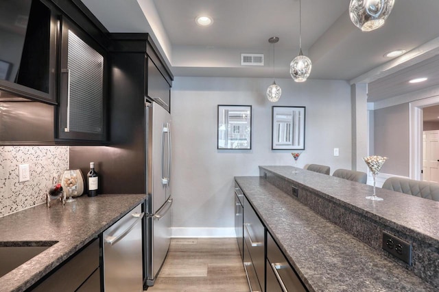 kitchen featuring tasteful backsplash, decorative light fixtures, light hardwood / wood-style flooring, a tray ceiling, and stainless steel appliances