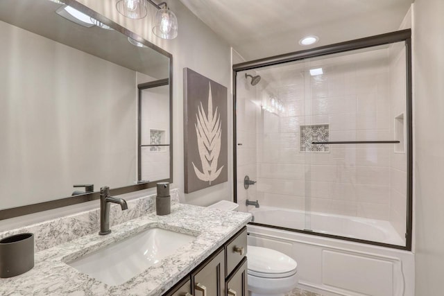 full bathroom featuring vanity, combined bath / shower with glass door, and toilet