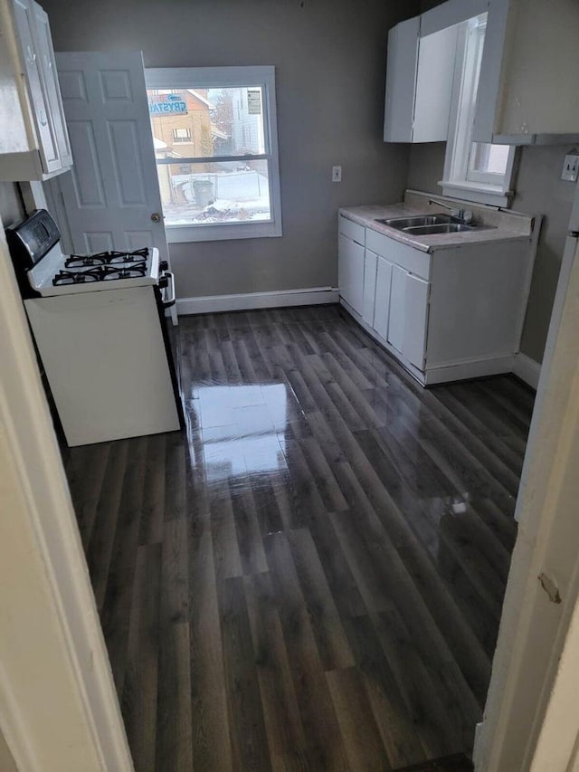 kitchen with sink, dark hardwood / wood-style flooring, white gas range oven, and white cabinets