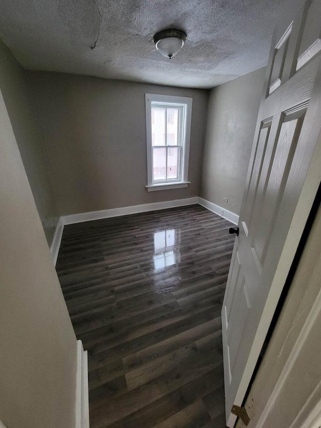 spare room featuring dark wood-type flooring and a textured ceiling