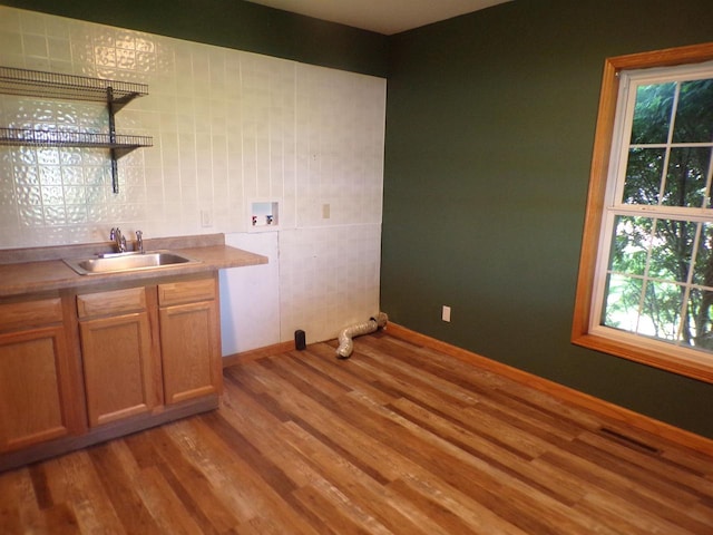 clothes washing area with hookup for a washing machine, light hardwood / wood-style flooring, sink, and a wealth of natural light