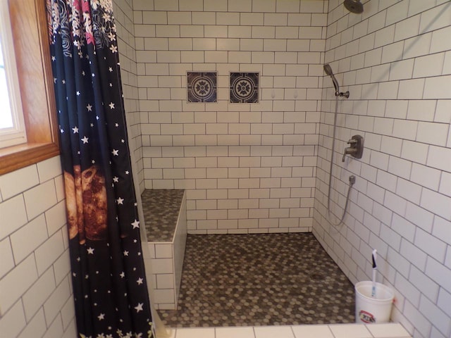 bathroom featuring a shower with curtain and tile walls