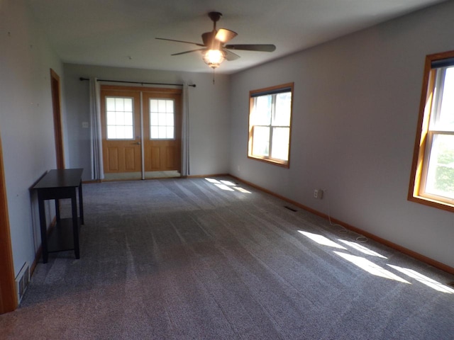 spare room with dark carpet and a wealth of natural light