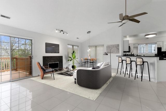 living room with ceiling fan, plenty of natural light, high vaulted ceiling, and light tile patterned floors