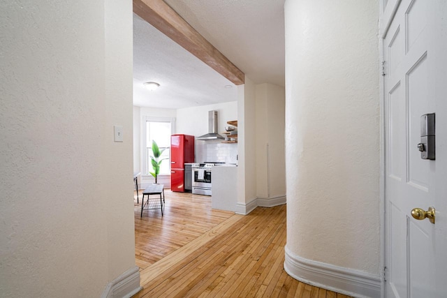 hall featuring beamed ceiling and light hardwood / wood-style floors