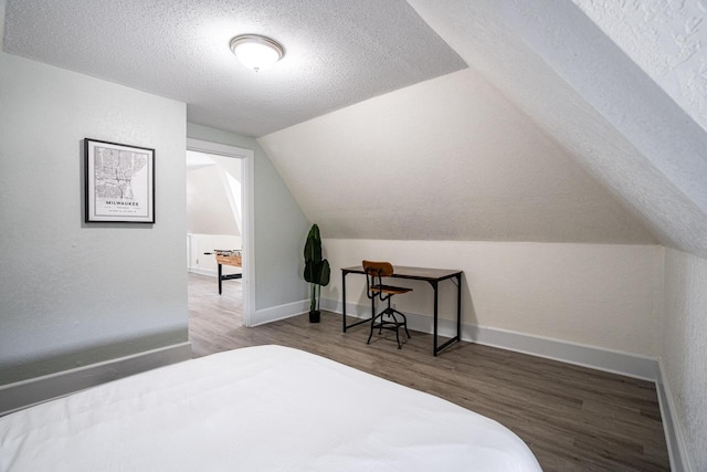 bedroom featuring hardwood / wood-style flooring, vaulted ceiling, and a textured ceiling