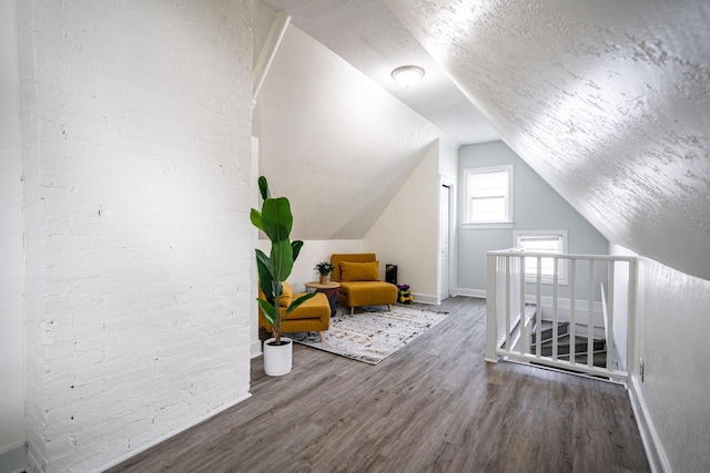 bonus room featuring wood-type flooring, vaulted ceiling, and a textured ceiling