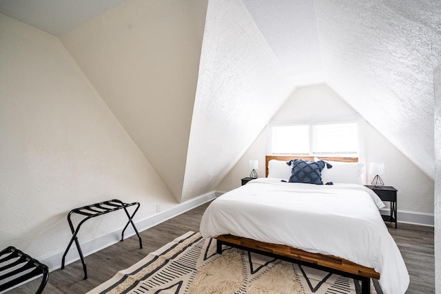 bedroom featuring lofted ceiling, dark hardwood / wood-style flooring, and a textured ceiling