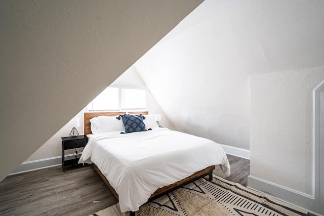 bedroom with dark hardwood / wood-style flooring, vaulted ceiling, and a textured ceiling