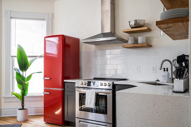 kitchen with sink, light hardwood / wood-style flooring, electric range, decorative backsplash, and wall chimney range hood