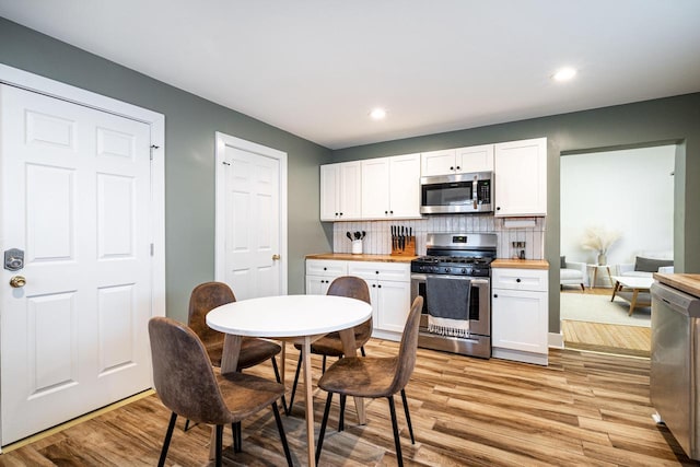 kitchen with wood counters, stainless steel appliances, light hardwood / wood-style floors, and white cabinets