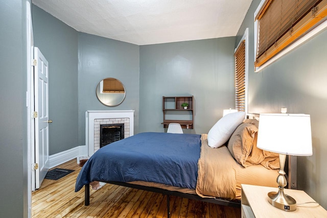 bedroom featuring a brick fireplace and light wood-type flooring