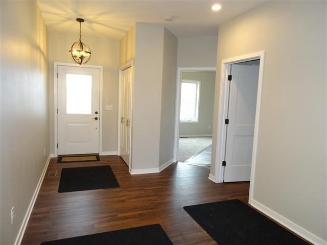 entrance foyer with an inviting chandelier and dark hardwood / wood-style floors