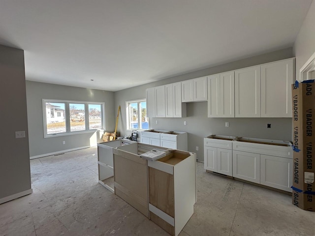 kitchen featuring a center island, white cabinets, and baseboards